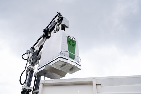 Garbage truck lifts street bin for recyclable waste