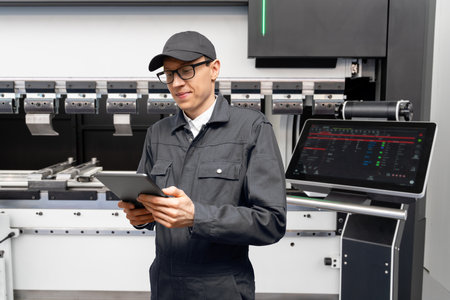 Worker with digital tablet controls automatic machine tool in smart factoryの写真素材
