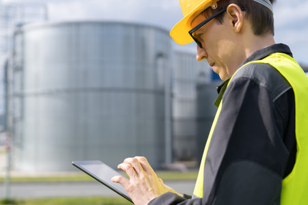 Engineer with digital tablet on a background of gas tanks.