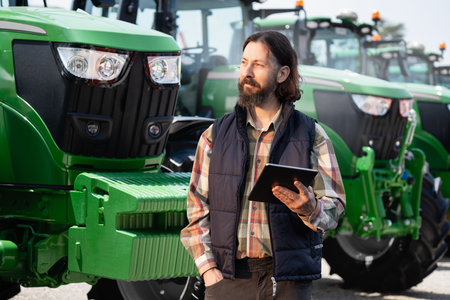 Farmer with a digital tablet on the background of an agricultural tractor.s