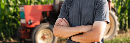 A farmer stands in front of a agricultural tractor.の写真素材