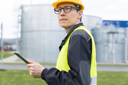 Engineer with digital tablet on a background of gas tanks.