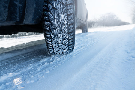 Car is on a snow covered winter road. Close up of winter tire.の写真素材