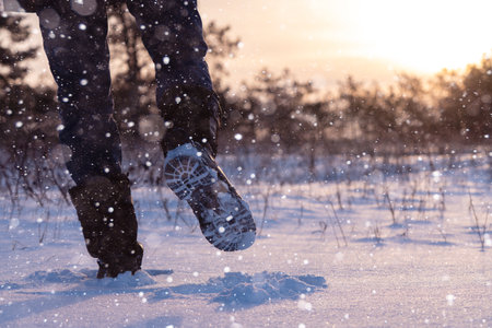 A traveler in boots walks along a snowy winter road.の写真素材