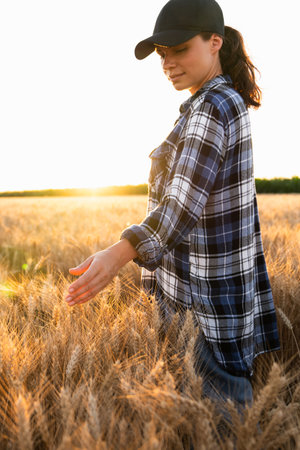 Woman farmer touches the ears of wheat on an agricultural field.