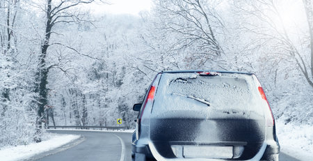 Car on a winter road through a snow covered forest
