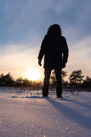 A traveler in boots walks along a snowy winter road.の写真素材