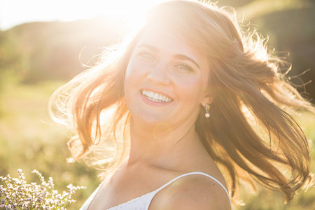 Smiling woman with flying hair at summer sunsetの写真素材