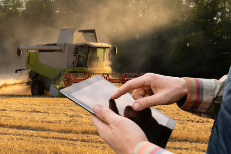 Farmer with digital tablet on a background of harvester. Smart farming concept