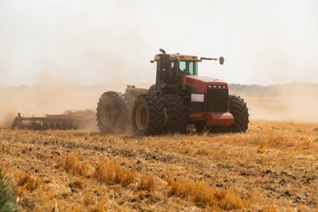 A tractor with a plow plows the field after harvesting
