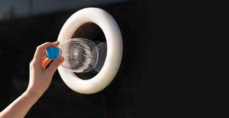 Woman uses a self service machine to receive used plastic bottles and cans on a city street.の写真素材