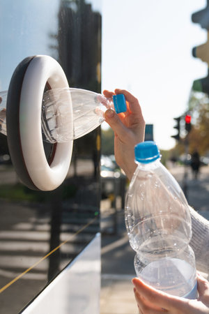 Woman uses a self service machine to receive used plastic bottles and cans on a city street.の写真素材