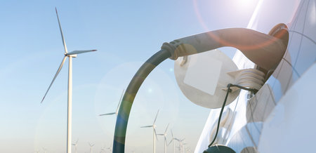 Electric car with charging plug on a background of wind turbines..の写真素材