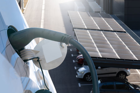 Electric car is charging from a charging station that takes energy from solar panels. Close up.の写真素材