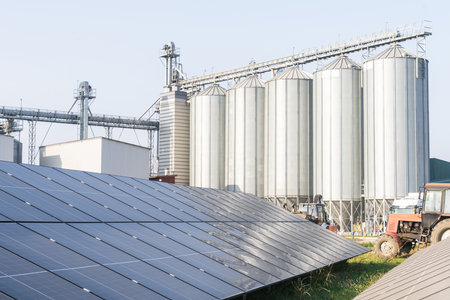 Modern farm using renewable energy. Solar panels with silos in the background