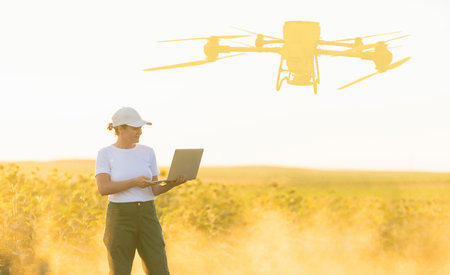 Woman farmer wearing white cap and t-shirt with laptop on agricultural field at sunset.