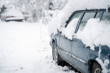 Parked car covered with snow during snow stormの写真素材
