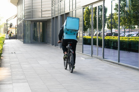 Delivery man with backpack is riding a bycicle.の写真素材