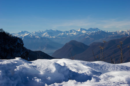 in the foreground a ridge covered with snow that opens up the view of the panorama of the snow-capped Alps in contrast with a beautiful blue skyの写真素材