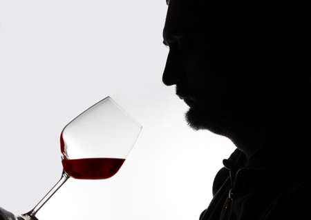 silouette on a white background of a sommelier holding a glass of fine Italian red wineの写真素材