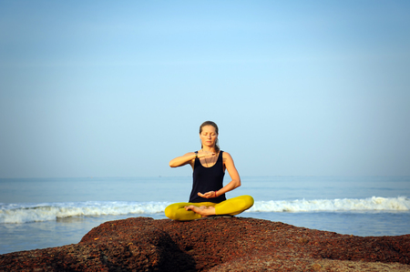 Beautiful young woman practicing yoga and stretching exercises at the summer tropic ocean  seashoreの写真素材