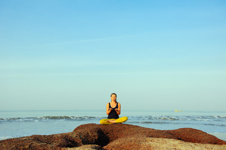 Beautiful young woman practicing yoga and stretching exercises at the summer tropic ocean  seashoreの写真素材