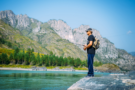 Fisherman on the mountain river at the nice summer day. Trout fly fishing in the mountain river with mountains in backgroundの写真素材
