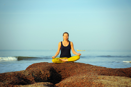 Beautiful young woman practicing yoga and stretching exercises at the summer tropic ocean  seashoreの写真素材