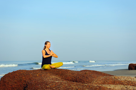 Beautiful young woman practicing yoga and stretching exercises at the summer tropic ocean  seashoreの写真素材