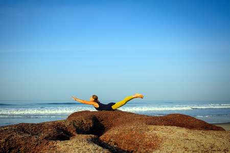 Beautiful young woman practicing yoga and stretching exercises at the summer tropic ocean  seashoreの写真素材