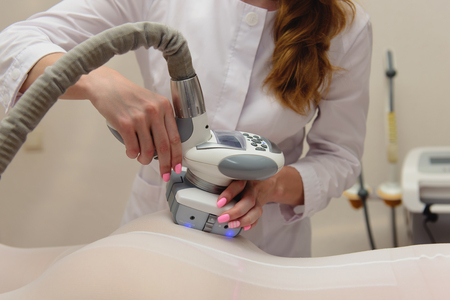 Lymphatic drainage massage LPG apparatus process. Woman in white suit getting anti cellulite massage in a beauty SPA salon. LPG, and body contouring treatment in clinic. Massage procedure on female body. Body care.の写真素材
