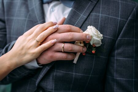 Hands of the bride and groom with elegant manicure, close-up. Wedding rings of the newlyweds, couple on wedding day, touching moment.の写真素材
