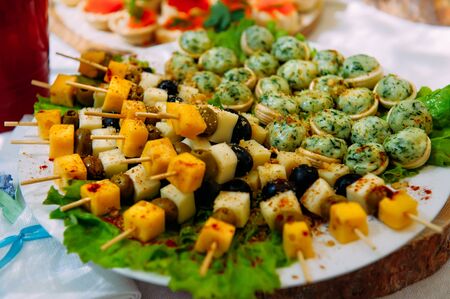 Tables in the restaurant with snacks and dishes. Easy food for guests. Business lunch. Preparing for wedding banquet. Smorgasbord. Mass event, coffee break. Catering service, self-service.の写真素材