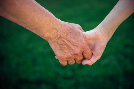 Grandmother holding grandchild hand in nature. National Grandparents Day, family concept. Two...