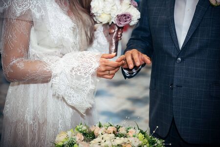 Bride and groom holding hands. Hands of the newlyweds and bride's bouquet. Wedding concept.の写真素材