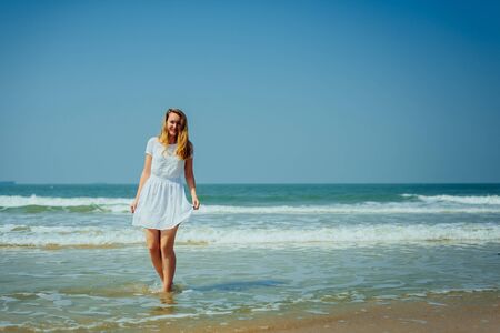 Beautiful Girl with Long Hairs in White Dress Enjoy and Relax on The Beach. Travel and Vacation.の写真素材