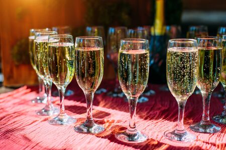 A row of glasses filled with cold champagne lined up, ready to be served. Glasses with Martini on the table - party background. Welcome drink on the wedding ceremony.の写真素材
