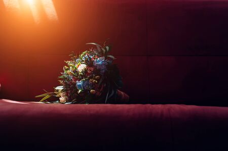Sunlight falls on the wedding bouquet of fresh flowers. Bride's bouquet on a dark background, close-up.の写真素材