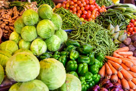 Abundance of vegetables in Asian street market. Heaps of various vegetables at bazaar in India, close up. Cabbage, carrots, eggplant, tomatoes, green paprika string beans.の写真素材