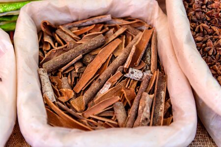 Cinnamon in the bag at Indian market close up. Small retail trade of spices in Asia.の写真素材