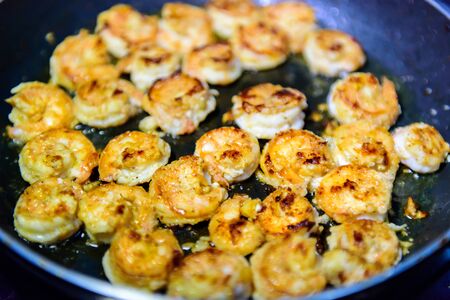 Process of roasting peeled shrimp with garlic in a frying pan, close-up. Prawns golden fried. Seafood delicious.の写真素材