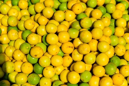 Lots of yellow and green lime fruits at asian street market, close-up. Citrus background.の写真素材