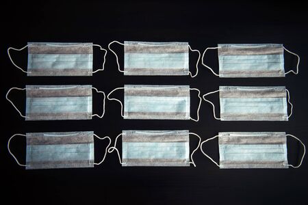 Medical masks in rows isolated on black. Blue surgical face masks on the table, close-up. Medical background. Concept of protection against viral infection.の写真素材