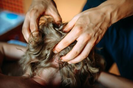 Woman gets professional head massage, close-up. Men's hands doing massage of the scalp.の写真素材