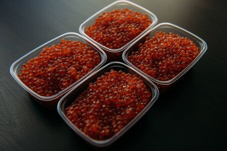 Lots of red caviar in jar. Sea food. Healthy eating. Red salmon caviar. Caviar in bowl over black background. Close-up. Delicatessen. Gourmet food.	の写真素材