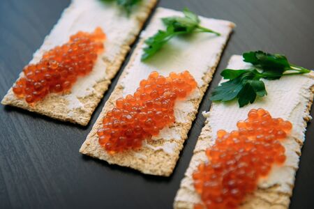Red caviar on crispy bread with cream cheese and green. Healthy food. Sandwiches with caviar...
