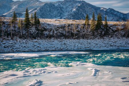 Unfrozen turquoise river in the mountains on a frosty winter day. Incredible mountain valley landscape in sunlight.の写真素材
