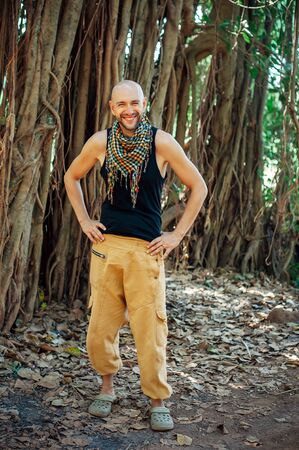Stylish young bald guy in a plaid neckerchief outdoors. Attractive, cheerful man poses for the...
