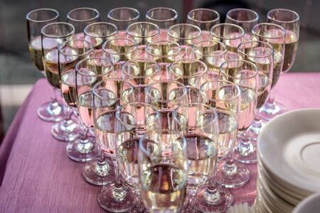 Glasses filled with champagne, close-up. Rows of glasses of white wine at festive dinner. Welcome drink.の写真素材