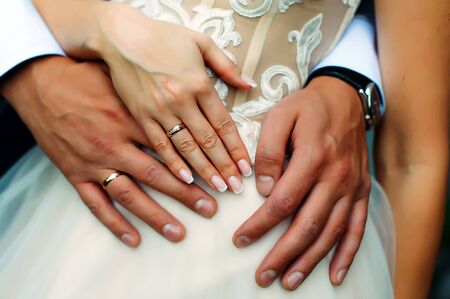 Close-up hands of bride and groom with wedding rings, newlyweds embracing. Concept of love, wedding and family.の写真素材